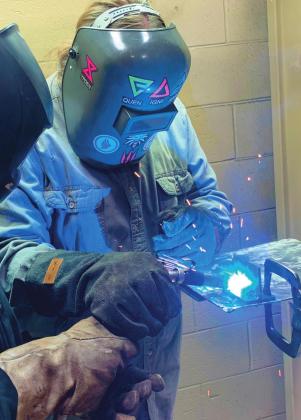 Central Tech adult welding student Colt Robertson, guides cosmetology student Kaliya Morgan, of Cushing, as she tack welds a T-plate during a community action project known as “Helping Hands” last Friday at the Drumright campus.
